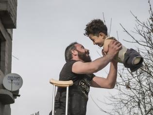 Φωτογραφία για Συγκλονίζει η φωτογραφία της χρονιάς: Ο ακρωτηριασμένος πατέρας και το παιδί του