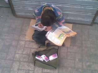 Φωτογραφία για Μια εικόνα που σοκάρει - Παιδάκι πουλάει χαρτομάντιλα και διαβάζει τα μαθήματά του